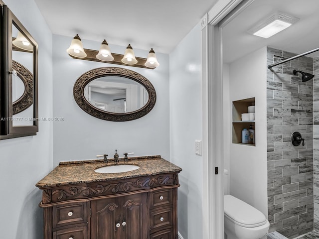 full bath with vanity, a tile shower, and toilet