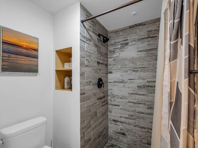 bathroom featuring a tile shower and toilet