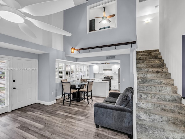 entryway with visible vents, a ceiling fan, wood finished floors, and a towering ceiling