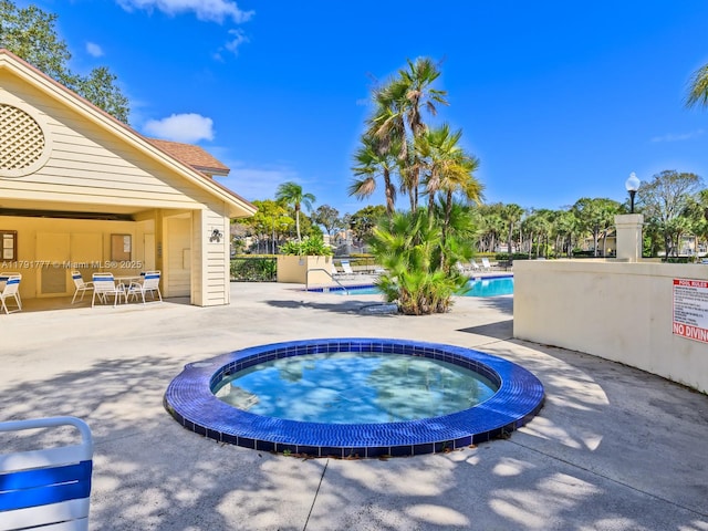 community pool featuring a hot tub and a patio area