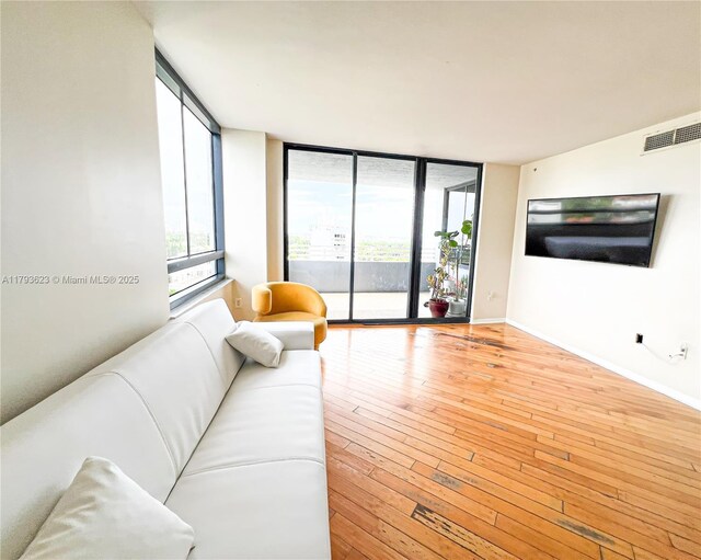 living area with visible vents, floor to ceiling windows, baseboards, and hardwood / wood-style floors