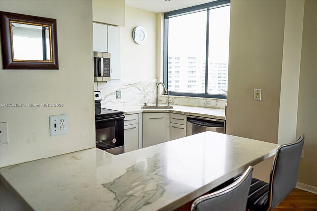 kitchen with a sink, appliances with stainless steel finishes, tasteful backsplash, and white cabinets