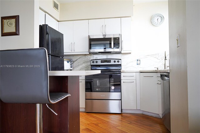 kitchen with light countertops, white cabinets, stainless steel appliances, and visible vents