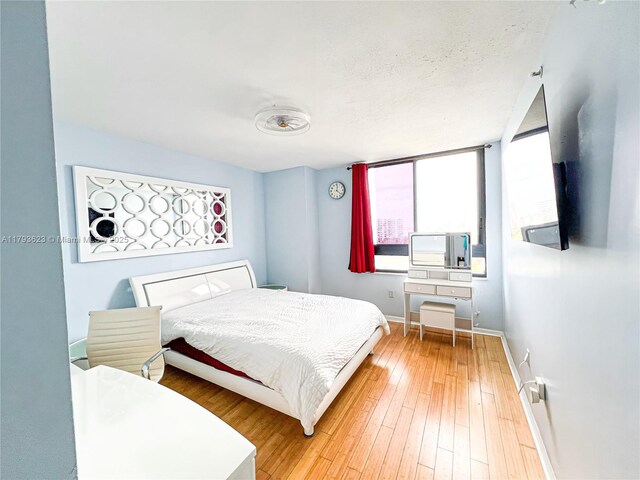 bedroom with baseboards, multiple windows, and hardwood / wood-style flooring