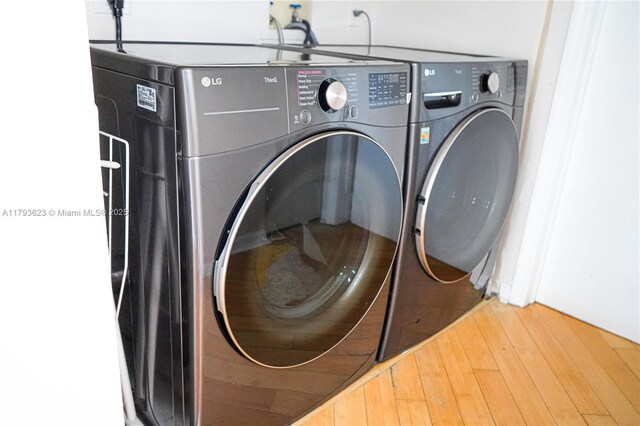 washroom with washing machine and clothes dryer, laundry area, and wood finished floors