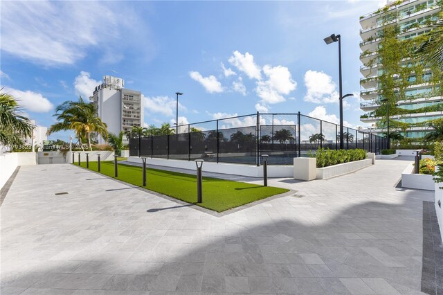 view of property's community with a tennis court and fence