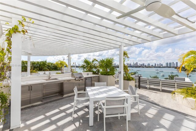 view of patio / terrace with a water view, outdoor dining area, a city view, an outdoor kitchen, and a pergola
