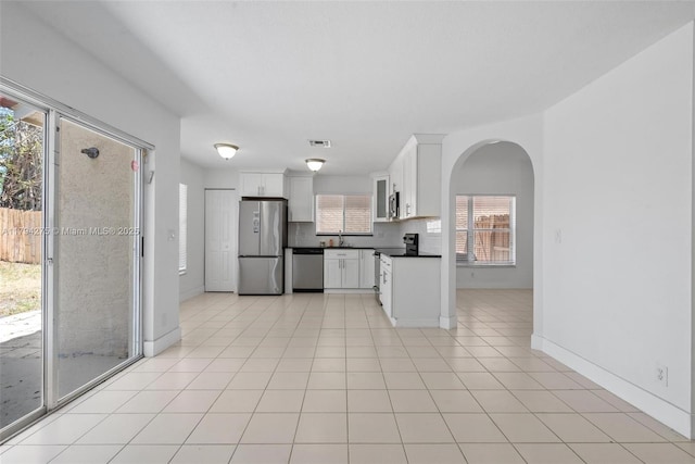 kitchen with white cabinets, dark countertops, a sink, stainless steel appliances, and visible vents