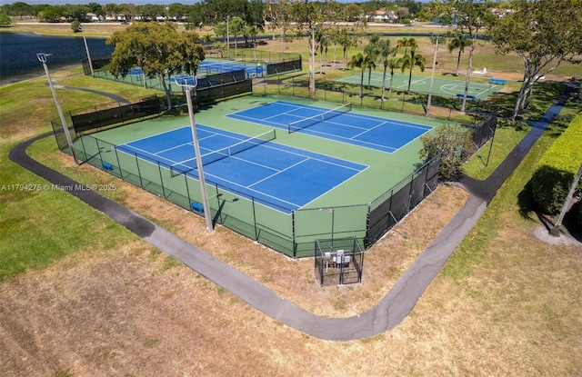 view of tennis court featuring fence and a yard