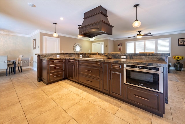 kitchen featuring oven, hanging light fixtures, a ceiling fan, and dark brown cabinets