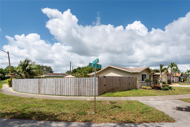 view of property exterior featuring a yard, stucco siding, fence, and a gate