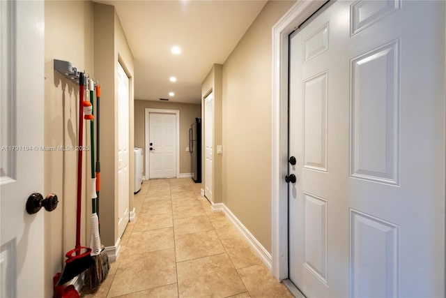 corridor featuring washer / dryer, light tile patterned floors, baseboards, and recessed lighting
