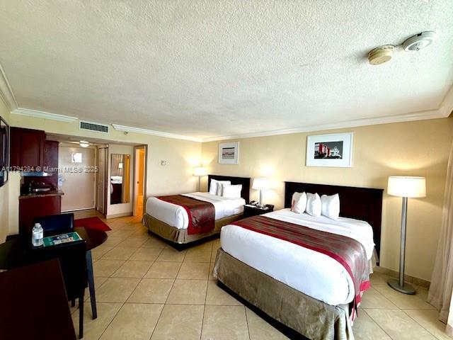 bedroom featuring visible vents, ornamental molding, a textured ceiling, and light tile patterned flooring