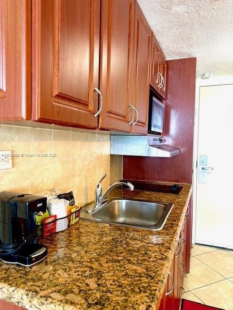 kitchen with decorative backsplash, a textured ceiling, white refrigerator with ice dispenser, a sink, and dark stone countertops