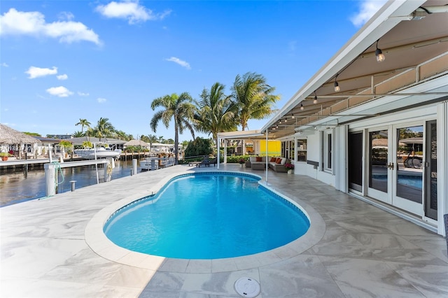 outdoor pool with a water view, outdoor lounge area, french doors, and a patio area