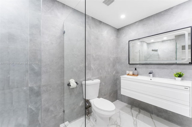 bathroom featuring visible vents, vanity, marble finish floor, toilet, and tile walls