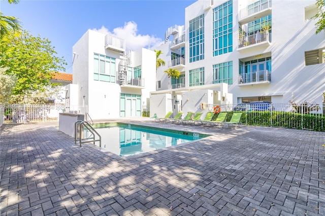 community pool with fence and a patio area
