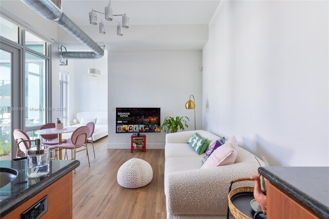 living area with light wood-type flooring, a chandelier, and baseboards