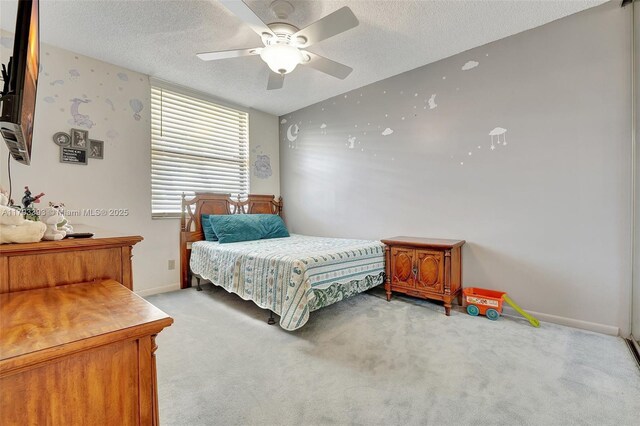 bedroom featuring baseboards, a textured ceiling, ceiling fan, and light carpet