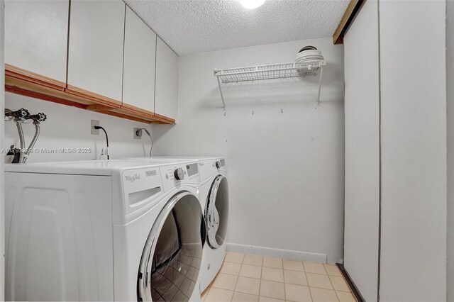 laundry area featuring cabinet space, a textured ceiling, baseboards, light tile patterned floors, and washing machine and dryer