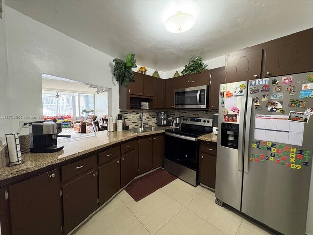 1680 NE 191st St Unit 118-2, Miami, FL 33179 - kitchen featuring appliances with stainless steel finishes, tasteful backsplash, dark brown cabinets, a sink, and light tile patterned flooring