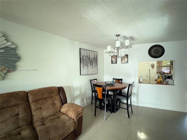 1680 NE 191st St Unit 118-2, Miami, FL 33179 - dining space with a textured ceiling, a notable chandelier, baseboards, and tile patterned flooring