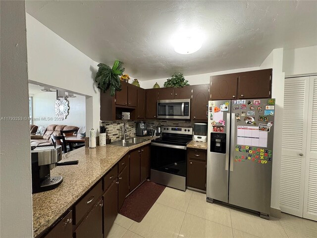 1680 NE 191st St Unit 118-2, Miami, FL 33179 - kitchen with decorative backsplash, light stone countertops, dark brown cabinets, a sink, and stainless steel appliances