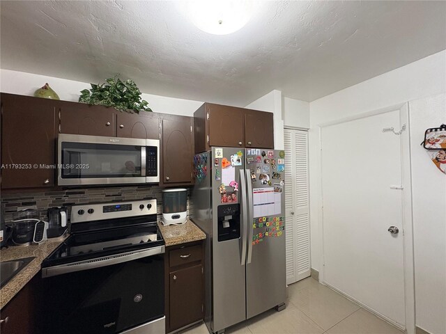 1680 NE 191st St Unit 118-2, Miami, FL 33179 - kitchen featuring light stone counters, light tile patterned floors, dark brown cabinetry, and stainless steel appliances