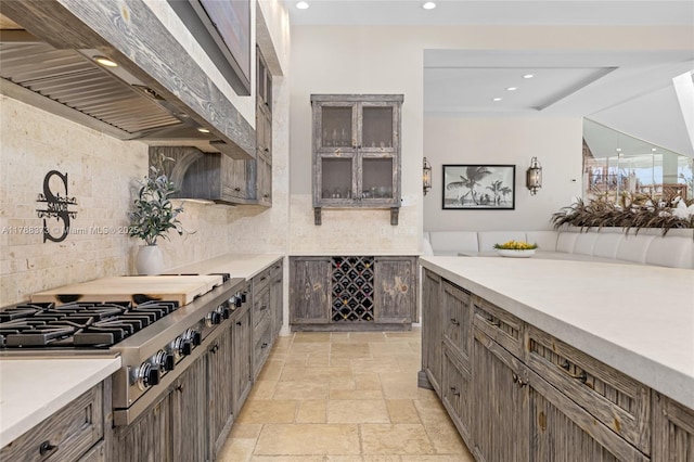 600 Isle Of Palms Dr, Fort Lauderdale, FL 33301 - kitchen with light countertops, extractor fan, stone tile floors, stainless steel gas stovetop, and tasteful backsplash
