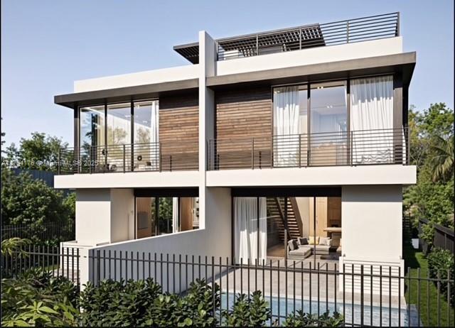 back of house with fence, stucco siding, and a balcony