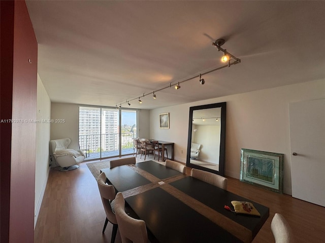 dining space featuring baseboards, rail lighting, and wood finished floors