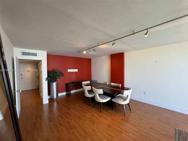 dining area with visible vents, rail lighting, baseboards, and wood finished floors