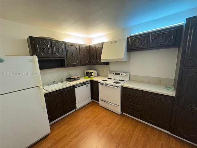 kitchen featuring exhaust hood, a sink, white appliances, light countertops, and light wood-type flooring