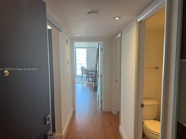 hall featuring baseboards, recessed lighting, and light wood-style flooring