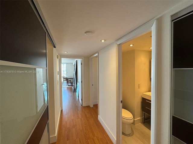 hall featuring recessed lighting, baseboards, and light wood-type flooring