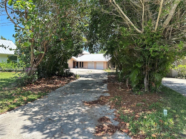 10737 SE Seaspray Ct, Hobe Sound, FL 33455 - view of property hidden behind natural elements featuring driveway and an attached garage