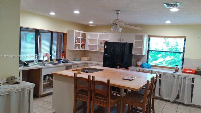 10737 SE Seaspray Ct, Hobe Sound, FL 33455 - kitchen featuring black appliances, open shelves, light tile patterned floors, light countertops, and recessed lighting