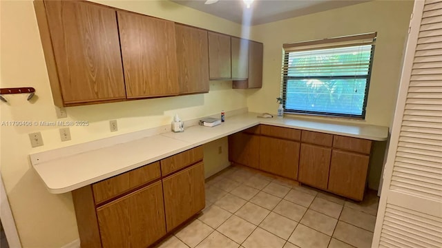 10737 SE Seaspray Ct, Hobe Sound, FL 33455 - kitchen with built in study area, light countertops, light tile patterned floors, and brown cabinetry