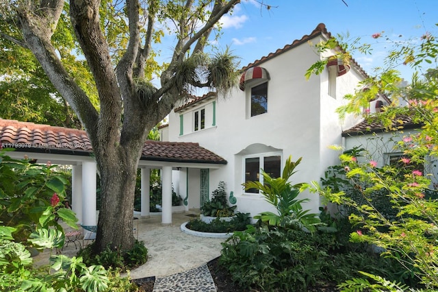 rear view of property with stucco siding and a tile roof
