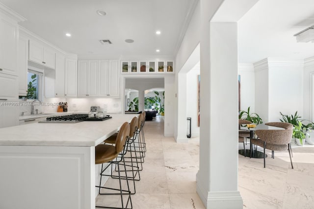 kitchen with visible vents, a sink, white cabinetry, and a breakfast bar area