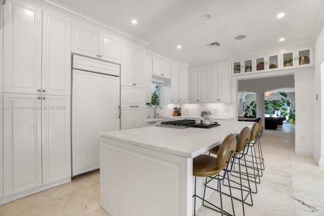 kitchen featuring a kitchen island, white cabinetry, paneled built in refrigerator, and a sink
