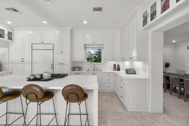 kitchen featuring visible vents, light countertops, paneled built in refrigerator, white cabinets, and black cooktop