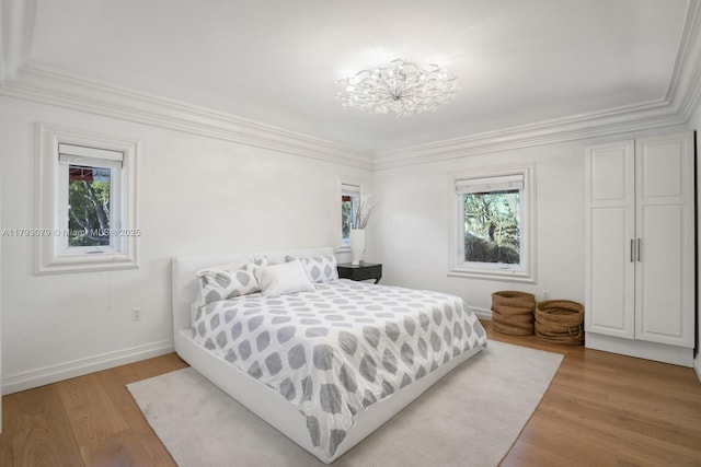 bedroom with baseboards, multiple windows, ornamental molding, and wood finished floors