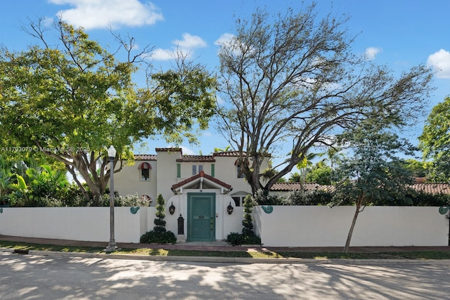 mediterranean / spanish home with a fenced front yard, stucco siding, and a tiled roof