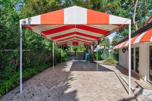 view of vehicle parking with fence, french doors, and a carport