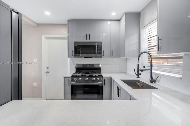 6501 Scott St, Hollywood, FL 33024 - kitchen with stainless steel appliances, gray cabinetry, a sink, and light stone counters