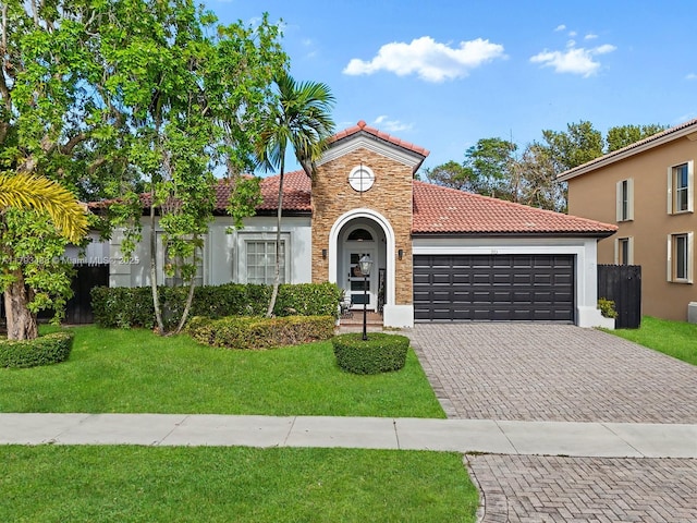 973 NE 36th Ave, Homestead, FL 33033 - mediterranean / spanish-style home featuring an attached garage, a front lawn, stone siding, decorative driveway, and a tiled roof
