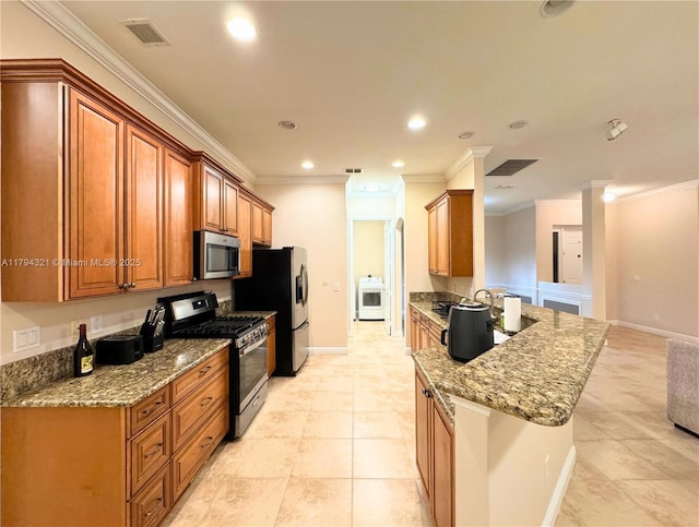kitchen with visible vents, ornamental molding, light stone countertops, washer / clothes dryer, and appliances with stainless steel finishes