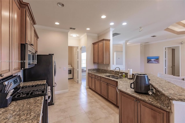 kitchen featuring appliances with stainless steel finishes, a sink, a peninsula, washer / dryer, and ornamental molding