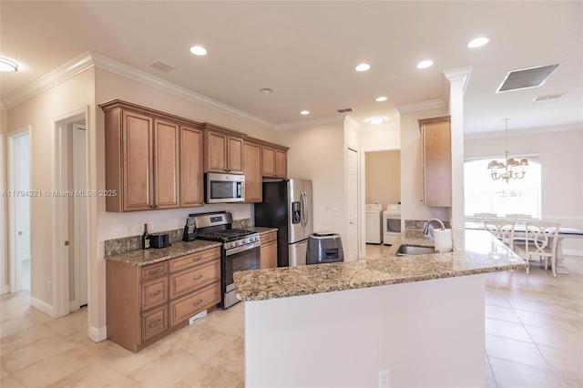 2041 SW Imperial St, Port St Lucie, FL 34987 - kitchen with stainless steel appliances, washer and clothes dryer, a sink, light stone countertops, and a chandelier